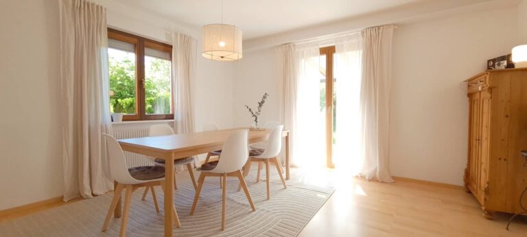 Esszimmer mit Holztisch, sechs Stühlen, Holzschrank und Fenstertür