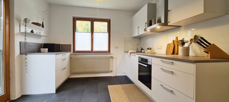 Helle Einbauküche mit Backofen, Kochfeld, Dunstabzug und Fenster