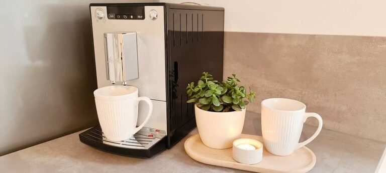 Kaffeevollautomat mit Tassen und Pflanze auf der Arbeitsplatte