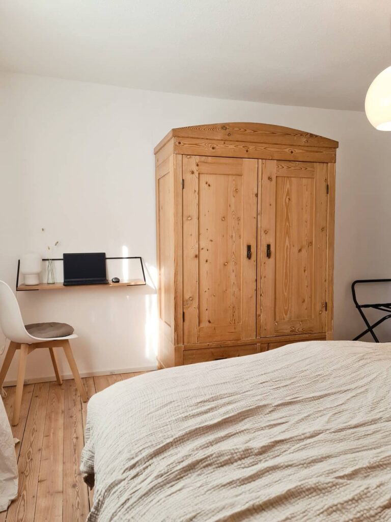 Schlafzimmer mit Holzkleiderschrank und kleiner Arbeitsecke