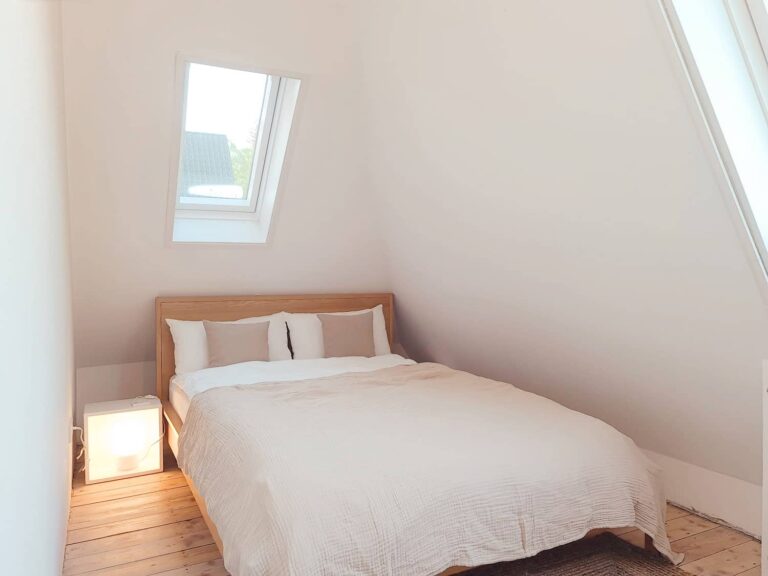 Schlafzimmer unter der Dachschräge mit Bett und Dachfenster